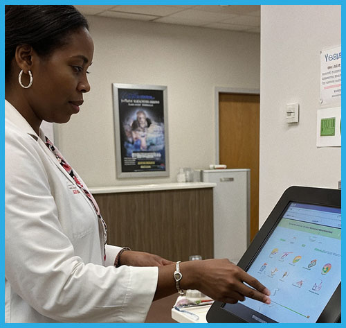 Woman using a Logic Controls self-service kiosk at a medical office.