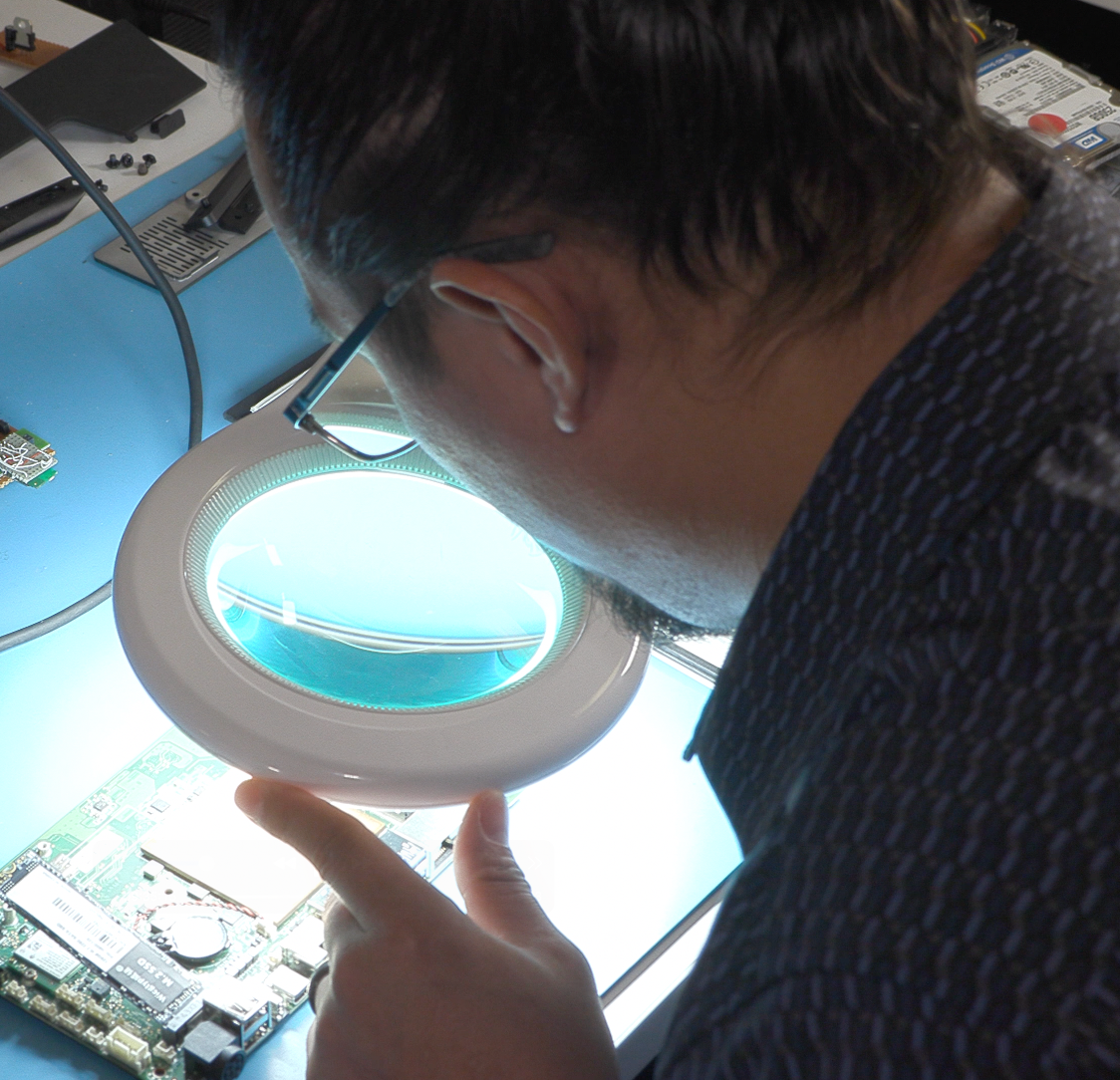 Logic Controls engineer viewing components of a motherboard under a magnifying glass.